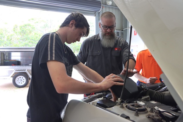 Automotive Students working on a car workshop with his trainer